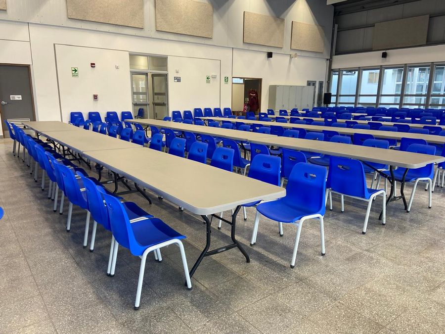Sillas de polipropileno azul dispuestas junto a mesas plegables