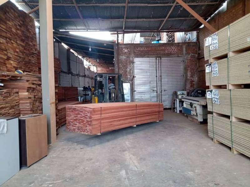 Almacén con planchas de melamina apiladas y montacargas trasladando madera